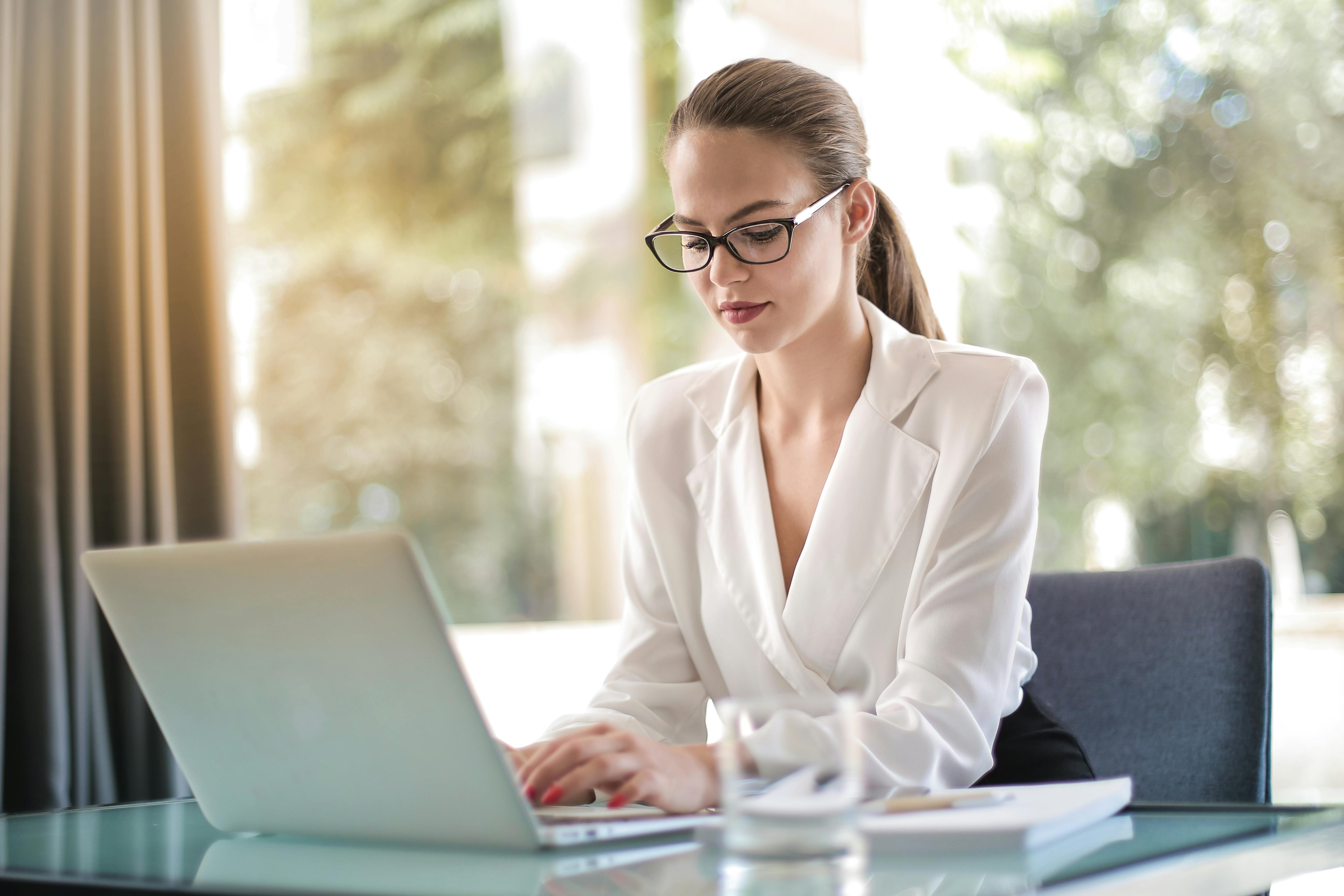 Woman in Glasses Reading on a Laptop
